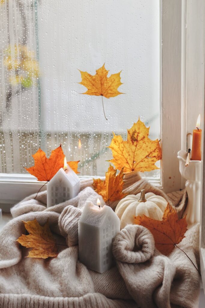 photo of candles pumpkin and yellow leaves in cozy interior